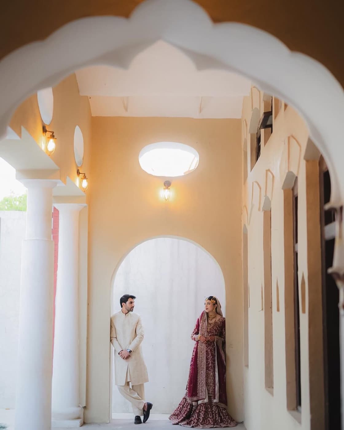 Couple standing beneath soft wedding arches