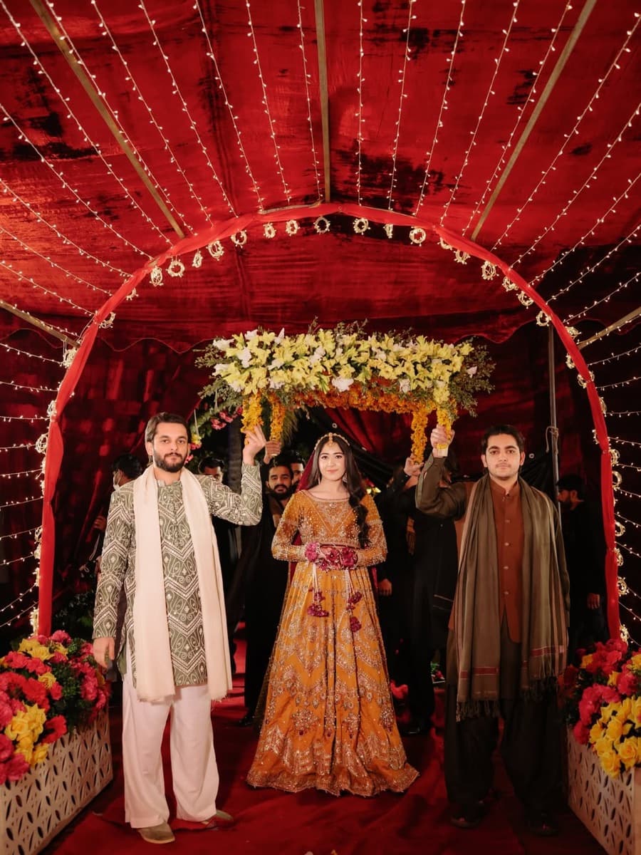Bride entering a wedding event under a red canopy